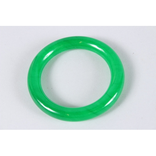 140 - A CHINESE APPLE GREEN JADE BANGLE. 3.25ins diameter.