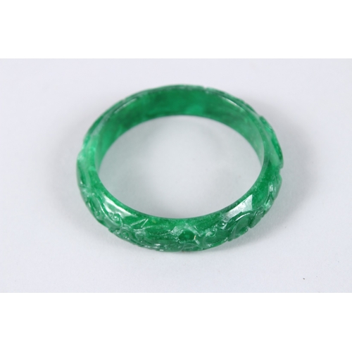141 - A CHINESE APPLE GREEN CARVED JADE BANGLE. 2.75ins diameter.