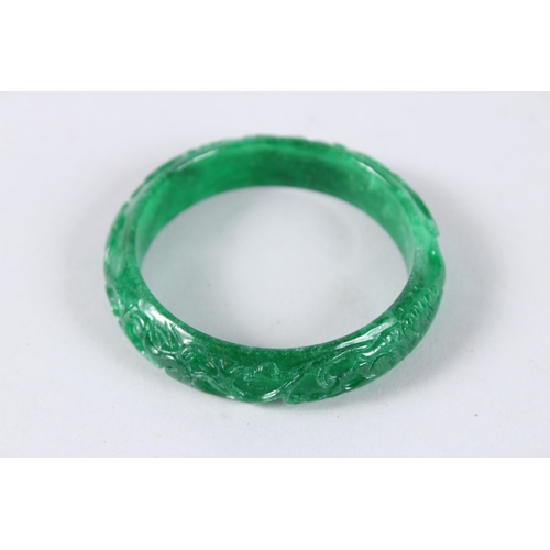 141 - A CHINESE APPLE GREEN CARVED JADE BANGLE. 2.75ins diameter.