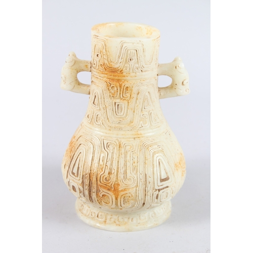 160 - A CHINESE ARCHAIC FORM CARVED JADEITE TWIN HANDLED VASE. 21cms high.