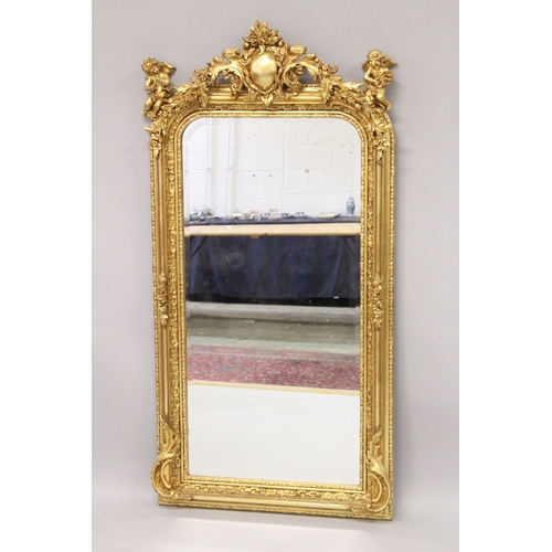 14 - A GOOD LOUIS XVI STYLE GILTWOOD MIRROR with scrolls and cupids. 6ft high x 2ft 8ins wide.
