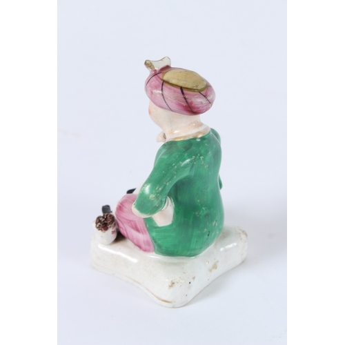 137 - A FIGURE OF A SEATED PORCELAIN TURKISH MAN SITTING GROSS-LEGGED ON A CUSHION. 10cms high.