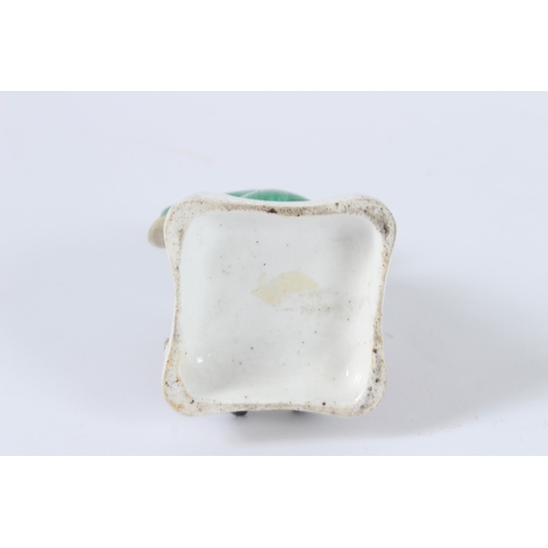 137 - A FIGURE OF A SEATED PORCELAIN TURKISH MAN SITTING GROSS-LEGGED ON A CUSHION. 10cms high.