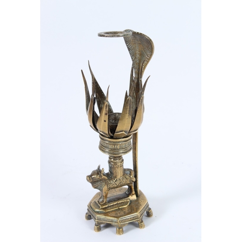 194 - A 19TH CENTURY INDIAN BRASS LOTUS LAMP , an animal holding a flower. 21cms high.