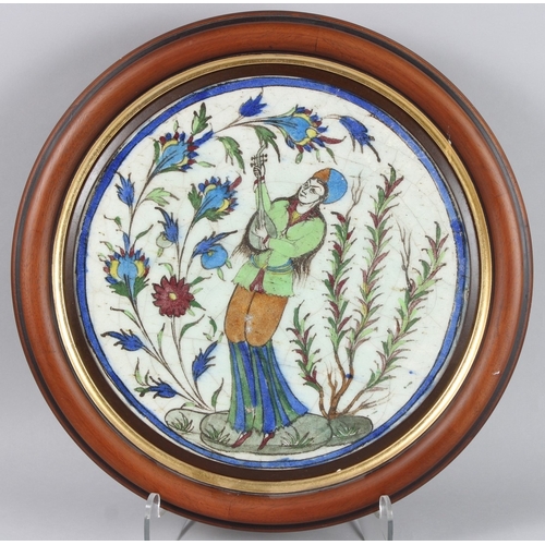 211 - A GOOD PERSIAN QAJAR 19TH CENTURY CERAMIC PLAQUE, a man holding a guitar surrounded by flowers. 14in... 