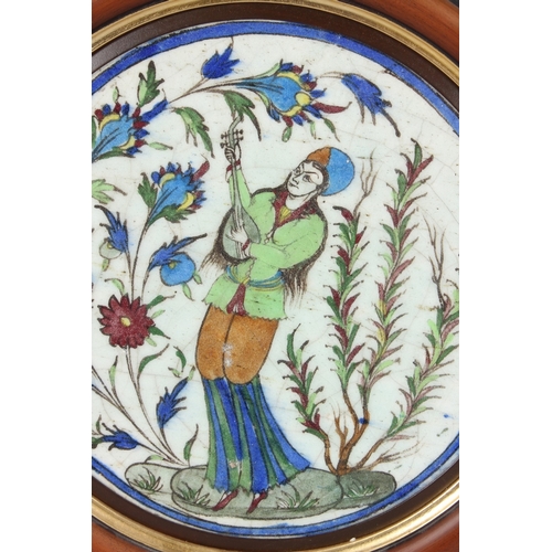 211 - A GOOD PERSIAN QAJAR 19TH CENTURY CERAMIC PLAQUE, a man holding a guitar surrounded by flowers. 14in... 