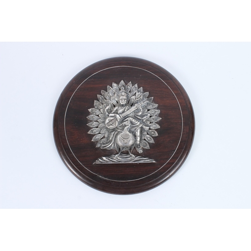227 - A FINE INDIAN SILVER HINDU DEITY on a wooden plaque. 23cms diameter.