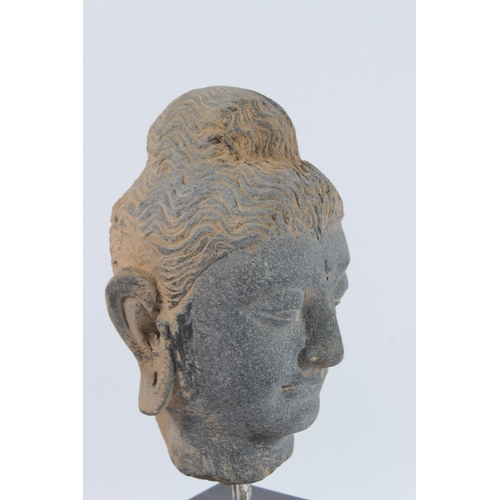 70 - A CARVED STONE HEAD OF BUDDHA from the GANDHARA REGION. 20cms high, on a marble base.