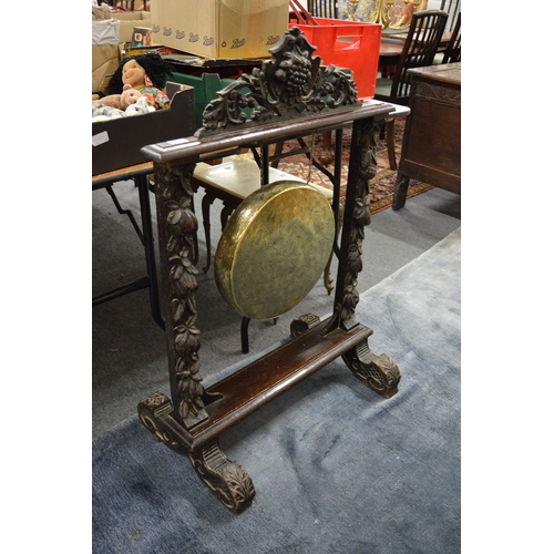350 - A brass dinner gong suspended on a carved oak frame.