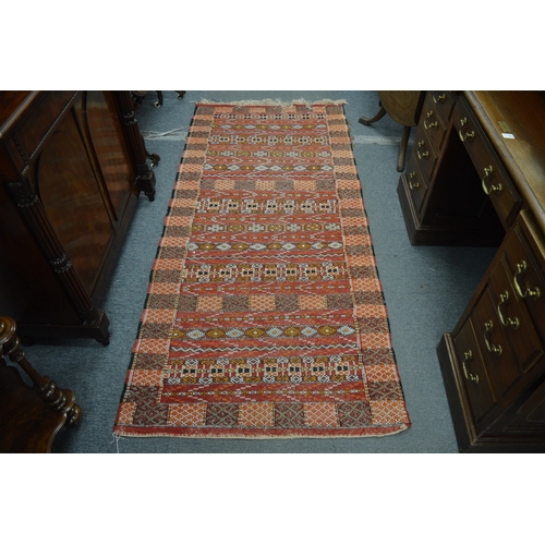 363 - An Eastern rug, red ground with geometric decoration, 211cm x 95cm.