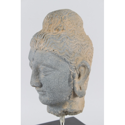 32 - A CARVED STONE HEAD OF BUDDHA from the GANDHARA REGION.  20cms high, on a marble base.