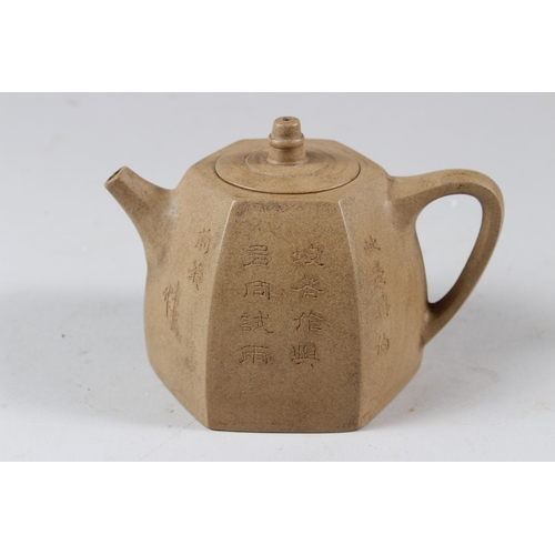 57 - A CHINESE YIXING POTTERY TEAPOT, of hexagonal form, incised with calligraphy.  15cms wide.