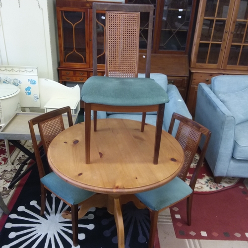 1416 - A pine circular table with three rattan backed dining chairs.