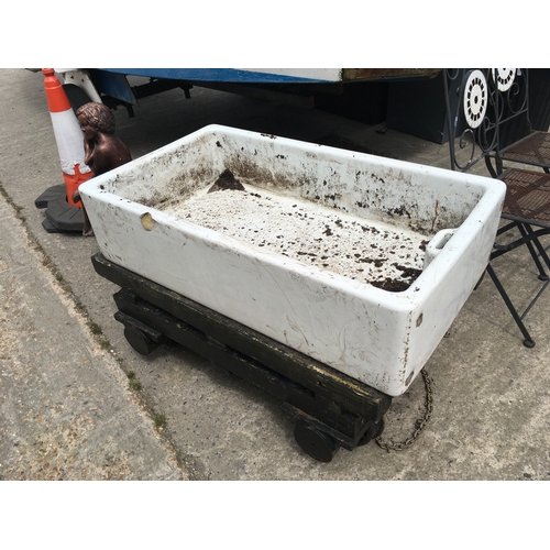 375 - A heavy duty bogie cart made with iron railway axels and carrying a large Belfast sink. 108cm x 75cm... 