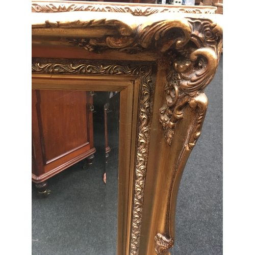 524 - An ornate gilt mirror with bevelled glass. 85x75cms.