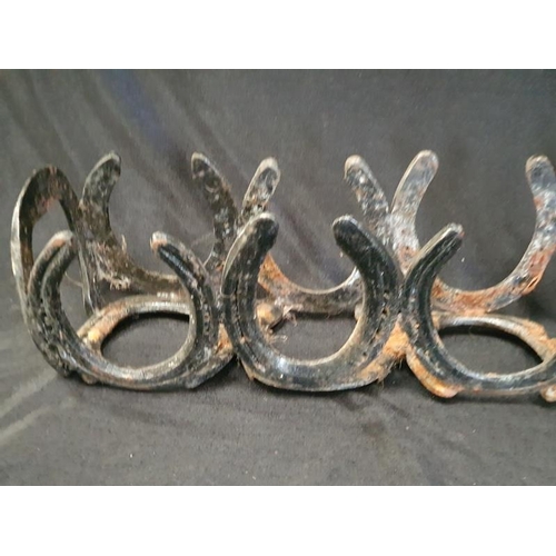 1060 - A vintage cast metal bottle rack depicting horse shoes.