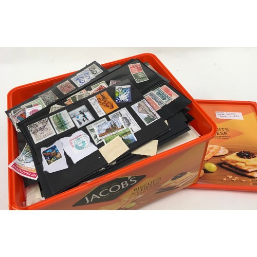 60 - large biscuit tub of loose world stamps. Some sorted.