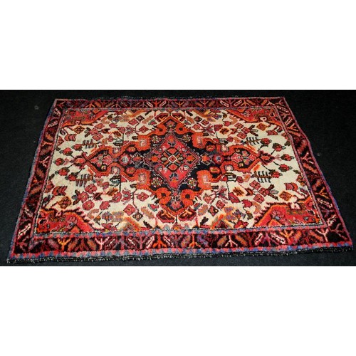 292 - Vintage hearth rug with age related wear. Mostly reds on a cream ground. 150cms x 110cms