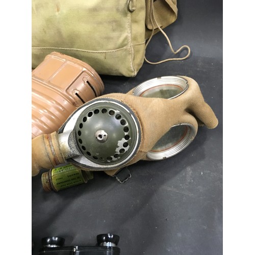 135 - Military interest: Vintage World War 2 era gas mask together with two military books and a miniature... 