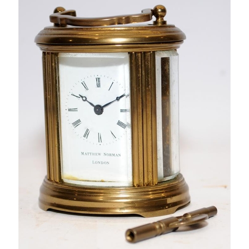 370 - Quality Matthew Norman miniature oval carriage clock with key. Seen working. All bevelled glass pane... 