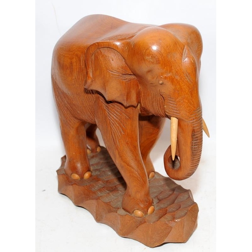 321 - A large wooden carved elephant c/w a similar resin elephant. Larger elephant is 30cms tall