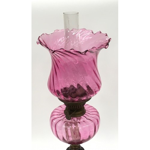 212 - Victorian cranberry glass oil lamp on cast iron base 64cm tall.