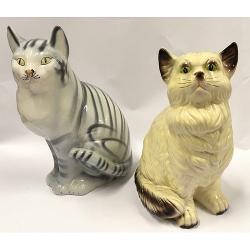 84 - A pair of ceramic sitting cat figurines the largest measuring 34cm.