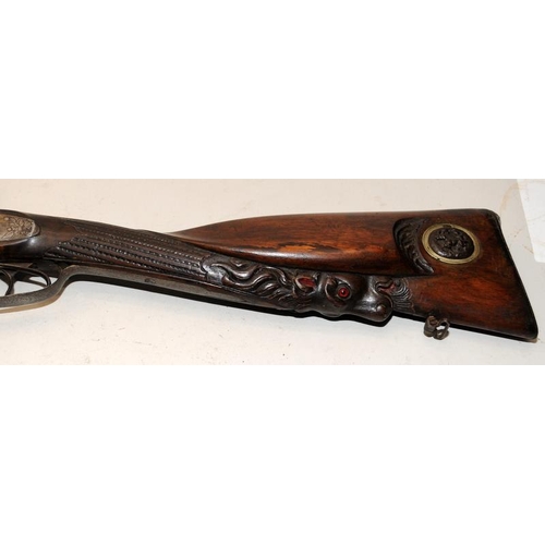 142 - Antique double barrel two trigger shotgun with ornately carved stock. O/all length 122cms. Mechanism... 