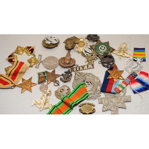 119A - A collection of WWI and WWII military cap badges, medals etc