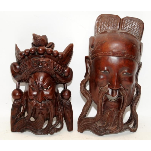 400 - Two vintage carved hardwood Oriental wallhanging face masks. The largest being 30cms