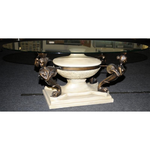 576 - Oval Glass top coffee table set on quatrefoil supports depicting maidens 45x120x60cm