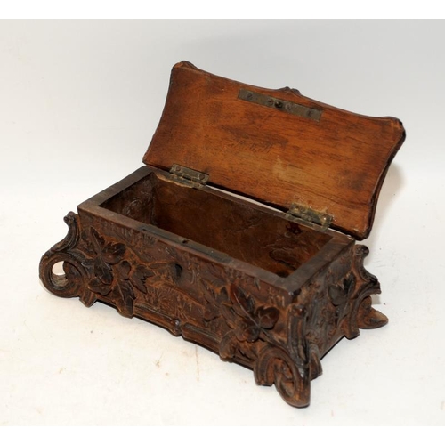 449 - A carved Black Forest casket with hinged lid featuring a hat and basket, with leaf decoration around... 