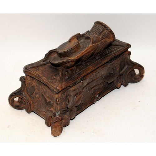 449 - A carved Black Forest casket with hinged lid featuring a hat and basket, with leaf decoration around... 