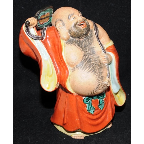 437 - Large vintage pottery figure of a laughing buddha with a fan. 21cms tall. Unsigned.