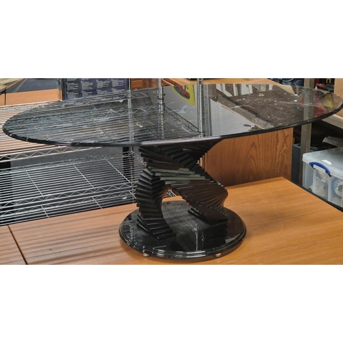 102 - Contemporary smoked black glass oval coffee table on stepped glass base 120x48x66cm.