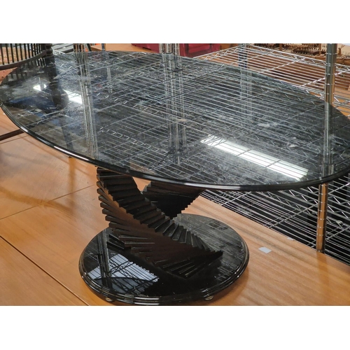 102 - Contemporary smoked black glass oval coffee table on stepped glass base 120x48x66cm.