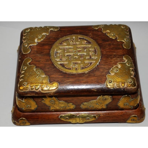 31 - Oriental hardwood lidded box on a separate base with applied brass decoration. 15cms across