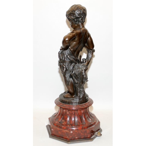 131 - A large 19th century bronze figure modelled on a red marble base of a child leaning against a tree s... 