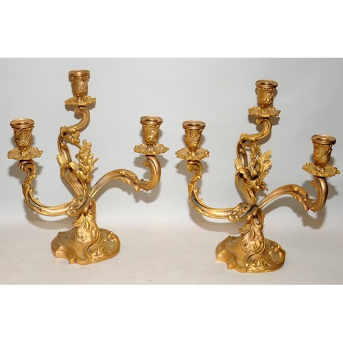 164 - Pair of rococo shaped ormolu three branch candelabra. 31cms tall