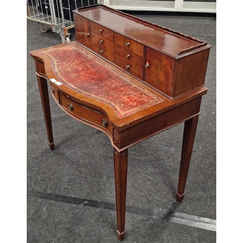 221 - Leather top ladies mahogany writing table having fitted exterior draws and cupboards, having a scall... 