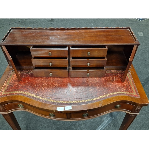 221 - Leather top ladies mahogany writing table having fitted exterior draws and cupboards, having a scall... 