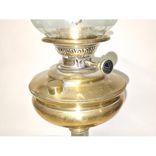 11 - Vintage large brass column oil lamp c/w green and opaque glass shade and chimney. 64cm tall.