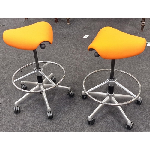 240 - A pair of contemporary gas lift swivel saddle seats on chrome bases with orange upholstery.