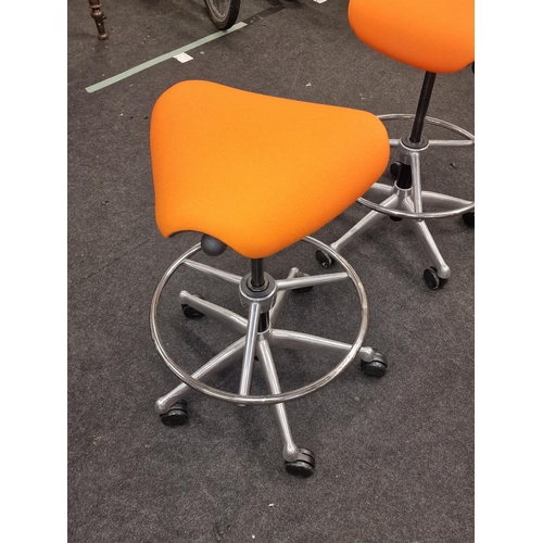 240 - A pair of contemporary gas lift swivel saddle seats on chrome bases with orange upholstery.