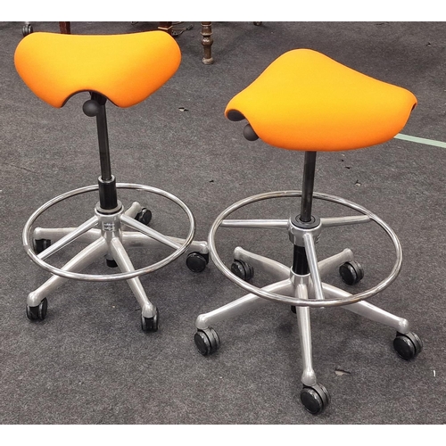 245 - A pair of contemporary gas lift swivel saddle seats on chrome bases with orange upholstery.