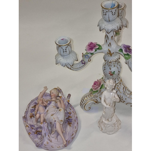 24 - Ornate Continental candlestick together with a pair of bisque wall plaques, and small figure (4)