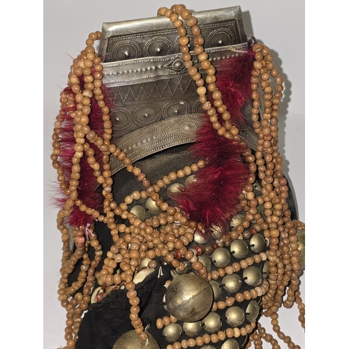 53 - An Asian ladies Akha headdress decorated with metal beads, pendants, red feathers etc.