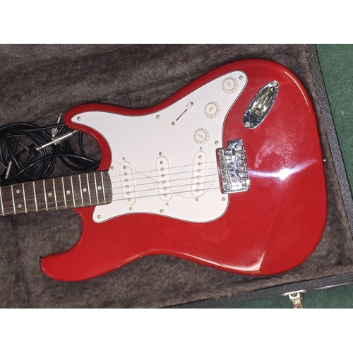53 - An Encore red Stratocaster style six string electric guitar c/w hard carry case and quartz guitar tu... 