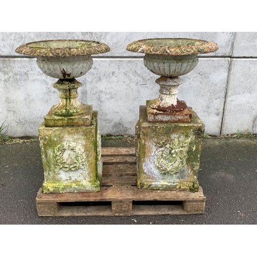 2 - LARGE CAST URNS ON TERRACOTTA PLINTHS