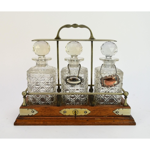 510 - An oak three-decanter tantalus, with electroplate mounts and two associated electroplate labels 'Bra... 